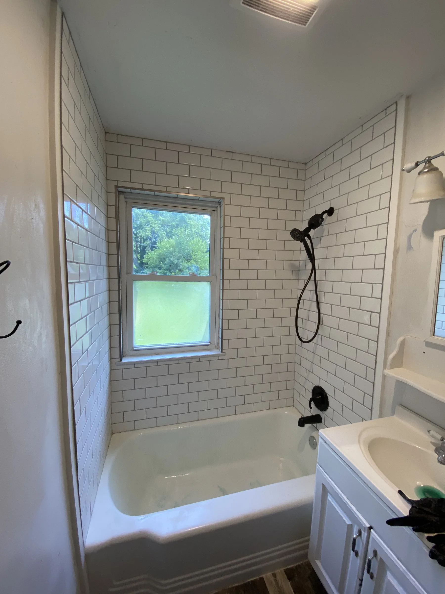 White subway tile tub and shower surround with gray grout and oil-rubbed bronze fixtures, completed by NextGen Bathroom Specialists